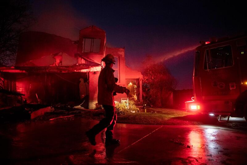 A firefighter assesses the damage of a home from the Tick Fire in Santa Clarita, California. AP Photo