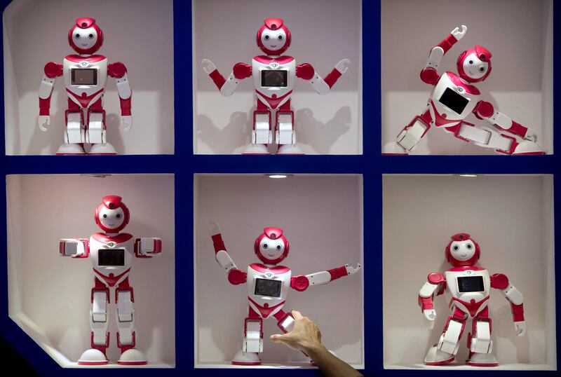 A visitor reaches for a robot on display at the World Robot Conference in Beijing. Mark Schiefelbein / AP Photo