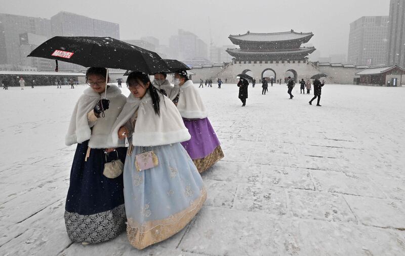 Visitors wearing traditional hanbok dress walk through Gyeongbokgung palace during snowfall in Seoul, South Korea. AFP