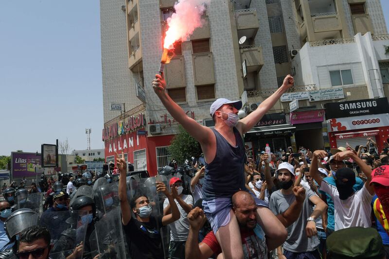 A Tunisian anti-government protester holds a flare during a rally in front of the Parliament.