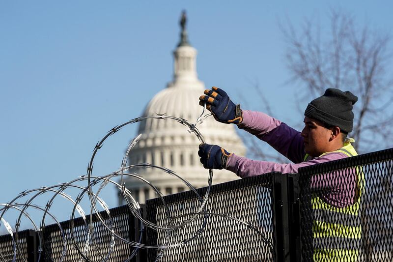 A worker removes razor wire from the top of security fencing as part of a easing of security measures put in place after the January 6 attack on the US Capitol in Washington. Reuters