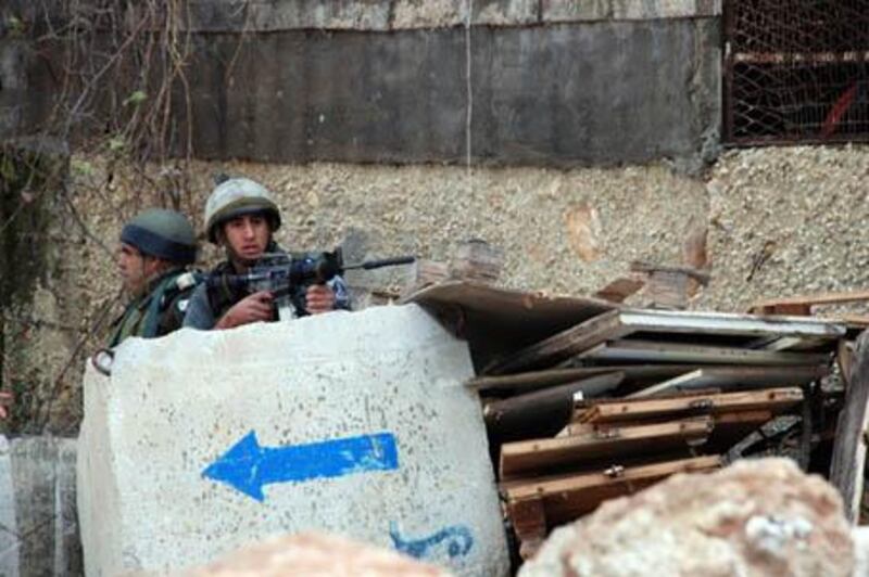 Israeli border policemen take cover behind a concrete block during a Palestinian demonstration in Beit Ur against the planned closure of Highway 443, 04 January 2008. Palestinian traffic is prevented from using Highway 443, which is mostly used as a 'bypass' commuter road linking large Israeli towns such as Modiin to Jerusalem, but is built on Palestinian territory in the West Bank. AFP PHOTO/AHED IZHIMAN