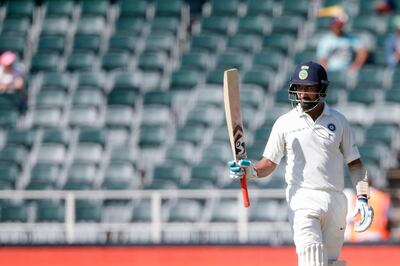 Indian batsman Cheteshwar Pujara raises his bat as he celebrates scoring a half-century (50 runs) during the first day of the third test match between South Africa and India at Wanderers cricket ground on January 24, 2018 in Johannesburg. / AFP PHOTO / GIANLUIGI GUERCIA
