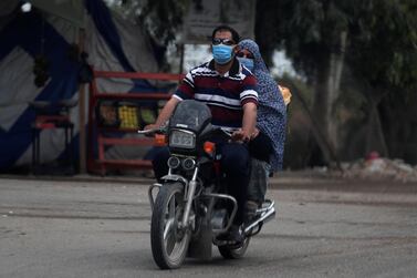 A man wearing a protective face mask to prevent the spread of the coronavirus disease (COVID-19) rides a motorcycle with his wife in Abu Kabir, north of Cairo, Egypt. Reuters