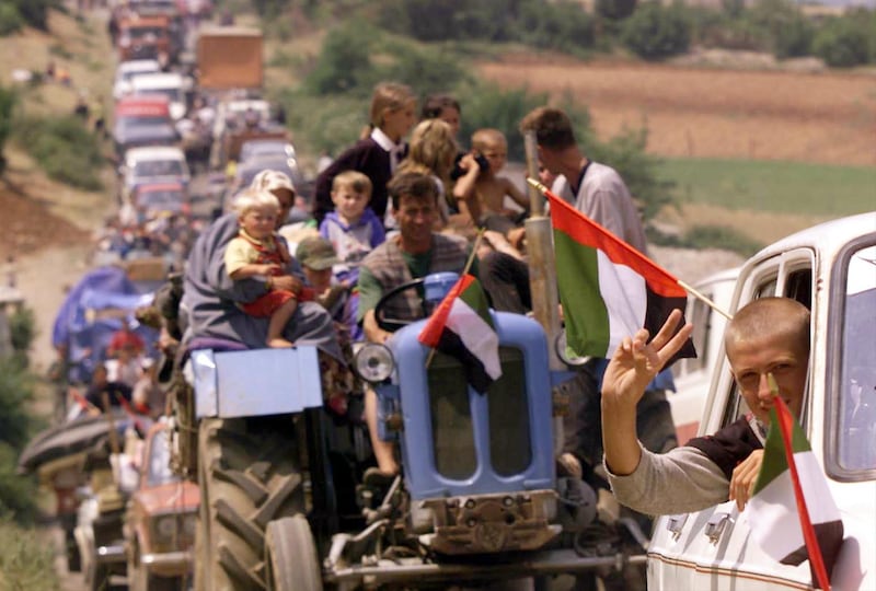 Thousands of refugees backed up for miles make their way across the border from Albania into Kosovo Wednesday June 16, 1999. There are more than 120,000 refugees in the Kukes area and thousands began heading home after weeks living in exile despite NATO and UNHCR warnings that their security is still not assured in Kosovo.  Flags are of the United Arab Emirates, who ran a refugee camp and contributed to the humanitarian aid effort in Albania. (AP Photo/David Guttenfelder)