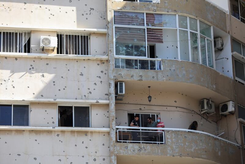 People stand on the balcony on a bullet-riddled building. Reuters