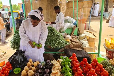 A greengrocer sets up his vegetables at a stall in Khartoum. AFP 