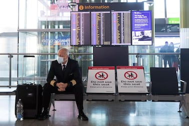 A member of flight crew sits next to social distancing signs in the check-in area at London Heathrow Airport. A new strain of the coronavirus has led to several countries banning passenger flights to and from the UK. Bloomberg