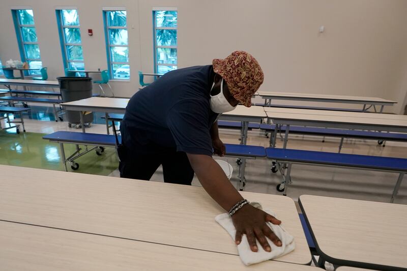 A school worker wipes down tables after students finished eating breakfast, on August 10, 2021, during the first day of school at Washington Elementary School in West Palm Beach, Florida, AP