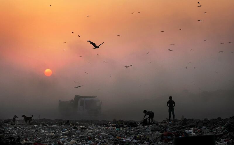 FILE- In this Oct. 17, 2014, file photo, a thick blanket of smoke is seen against the setting sun as young ragpickers search for reusable material at a garbage dump in New Delhi, India. India launched the Air Quality Index Friday to measure air quality across the nation that is home to some of the most polluted cities in the world. A groundbreaking agreement struck Wednesday, Nov. 12, 2014, by the United States and China puts the world's two worst polluters on a faster track to curbing the heat-trapping gases blamed for global warming. (AP Photo/Altaf Qadri, File)