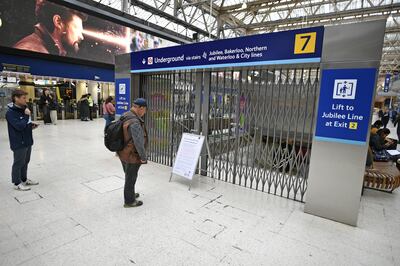 Commuters read a sign next to locked gates in Waterloo Station. PA
