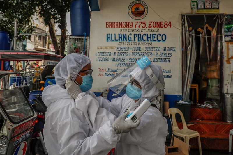 Health care worker Vannessa Morales (R) adjusts Richell Arsenio's hair cover before doing their rounds at a townhall in Manila, Philippines. They are part of a group of four volunteer health workers who were nicknamed 'Astronauts' by residents of Village 775, Zone 84 in Manila as they resemble such when donning their protective equipment. The healthcare volunteers conduct home visits twice a day to people infected or suspected to be infected with the novel SARS-CoV-2 coronavirus that causes the COVID-19 disease in one of the densely populated villages in Manila.  EPA