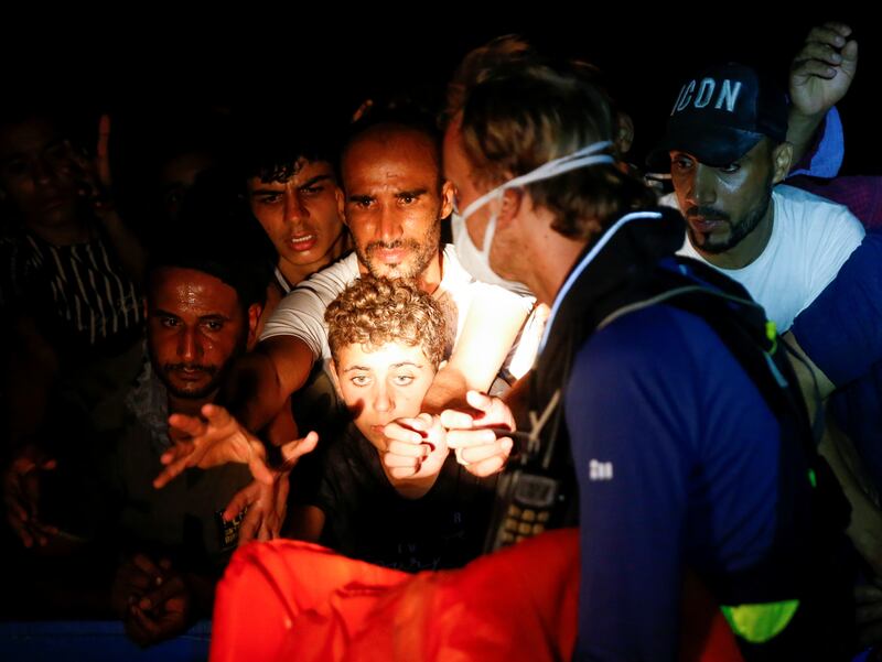 A crew member from the German NGO migrant rescue ship ‘Sea-Watch 3’ distributes life jackets to migrants.
