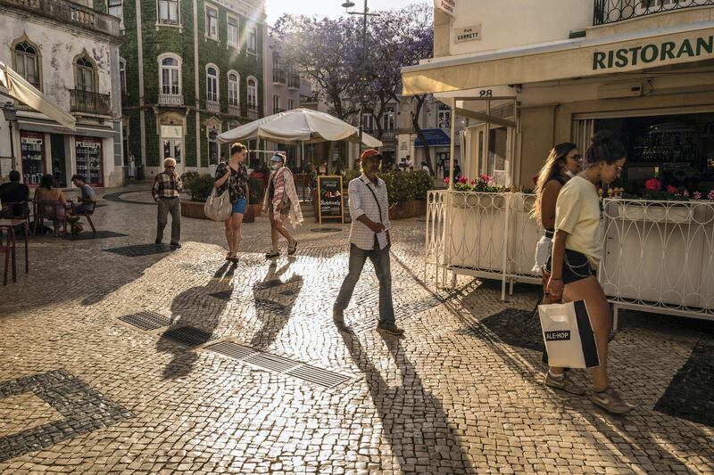 Tourists walk through a square past restaurants and cafes in Lagos, Portugal, on Sunday, May 30, 2021. Portugal is likely to raise its economic growth forecast for this year to close to 5% as tourists help boost the recovery and Europe’s Covid-19 vaccination campaign advances. Photographer: Jose Sarmento Matos/Bloomberg