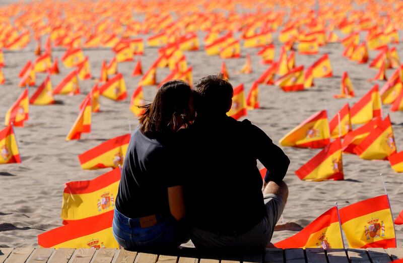A couple sits close to thousands of Spanish flags, representing the Spanish victims of COVID-19, on Patacona beach in Valencia. Spain has so far claimed more than 32,000 lives and 790,000 infected in the highest infection rate in the European Union. AFP