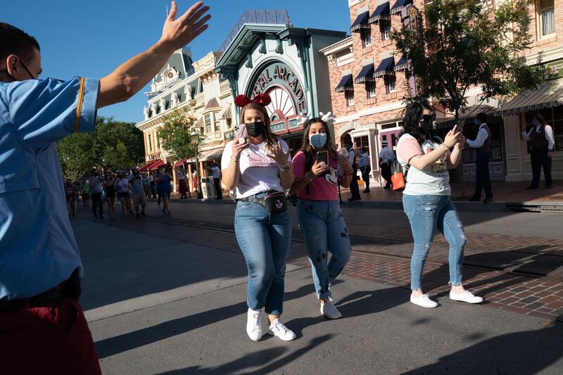 An employee greets returning guests wearing protective masks on Main Street USA during the reopening of the Disneyland theme park in Anaheim, California, U.S., on Friday, April 29, 2021. Walt Disney Co.'s original Disneyland resort in California is sold out for weekends through May, an indication of pent-up demand for leisure activities as the pandemic eases in the nation's most-populous state. Photographer: Bing Guan/Bloomberg