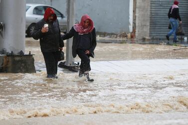 People cross a flooded street during heavy rains in Amman, Jordan on February 28, 2019. Reuters