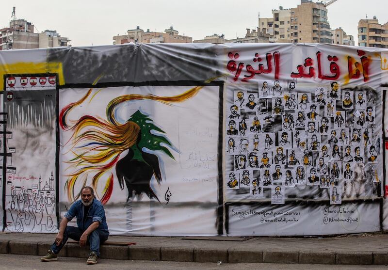 A protester sits next a graffiti with Arabic words reading 'I am the leader of revolution' at Riad El-Solh square in downtown Beirut.  EPA
