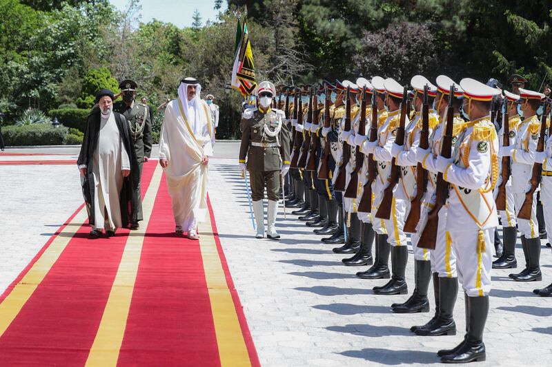 Mr Raisi walks with Sheikh Tamim at the presidential palace in Tehran. EPA