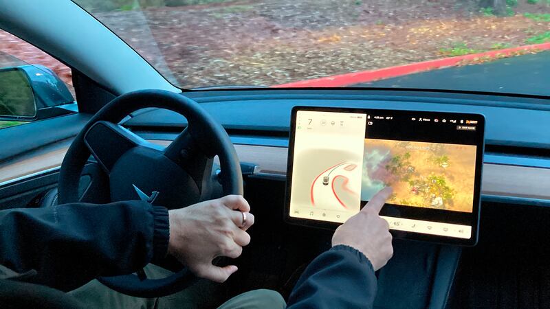 Vince Patton, a new Tesla owner, demonstrates on a closed course how he can play video games on the vehicle's console while driving. AP