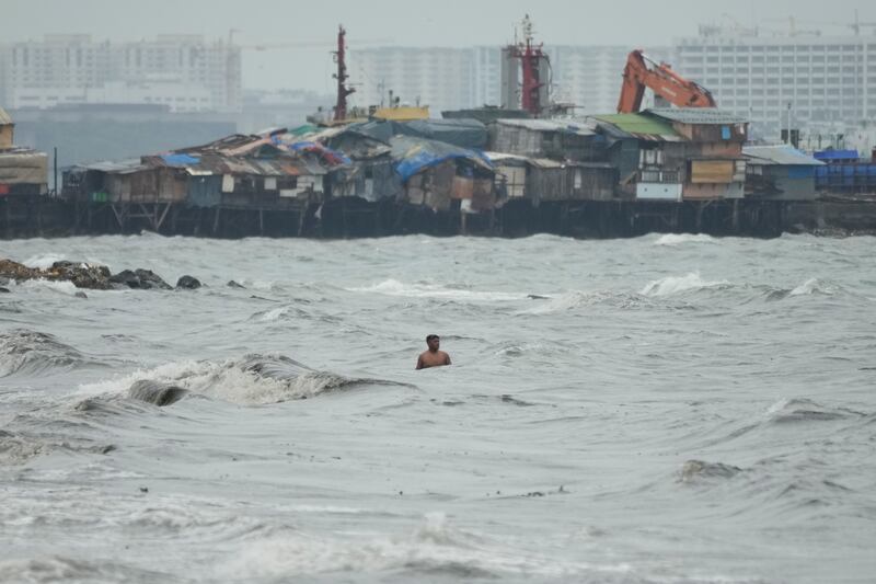 A resident swims in rough waters as the storm approaches the seaside slum district of Tondo in Manila. AP