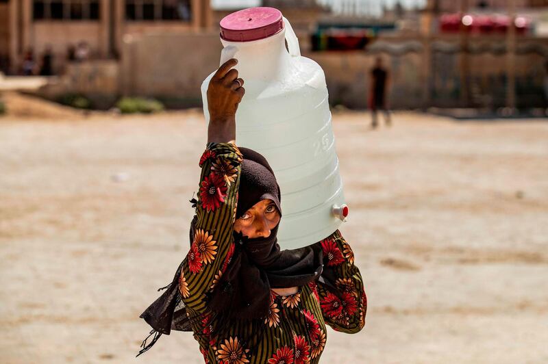 TOPSHOT - A displaced Syrian brings water back to their camp in a camp for the displaced in Syria's northeastern city of Hasakah on August 24, 2020.  / AFP / Delil SOULEIMAN
