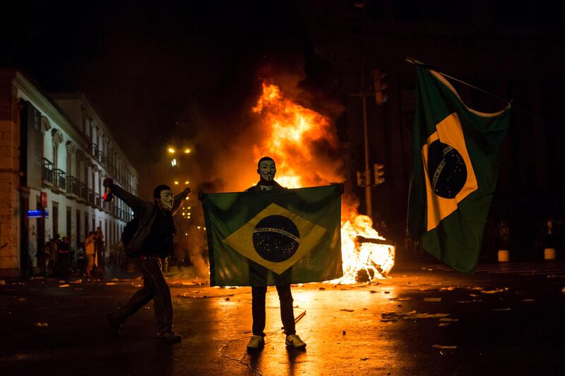 A demonstrator holds a Brazilian flag in front of a burning barricade during a protest in Rio de Janeiro in Rio de Janeiro, Brazil, Monday, June 17, 2013. Protesters massed in at least seven Brazilian cities Monday for another round of demonstrations voicing disgruntlement about life in the country, raising questions about security during big events like the current Confederations Cup and a papal visit next month. (AP Photo/Felipe Dana) *** Local Caption ***  Brazil Confed Cup Protests.JPEG-08acd.jpg