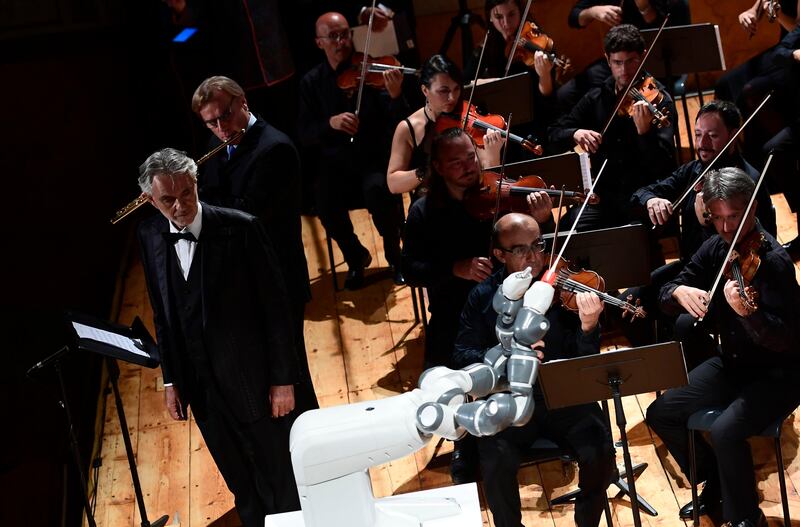 This photograph taken on September 12, 2017, shows Italian flutist Andrea Griminelli (2L) and Italian tenor Andrea Bocelli (L)
as they and The Lucca Philharmonic Orchestra are conducted by robot 'Yumi' for the first time at The Teatro Verdi in Pisa.  / AFP PHOTO / MIGUEL MEDINA