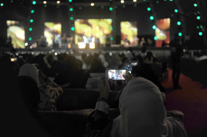 A Saudi woman ses her mobile phone to take a picture during a concert by Egyptian pop sensation Tamer Hosny. Amer Hilabi / AFP