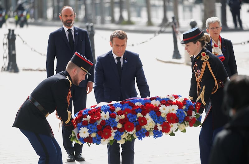 Mr Macron lays a wreath of flowers during a ceremony at the Arc de Triomphe in Paris. EPA