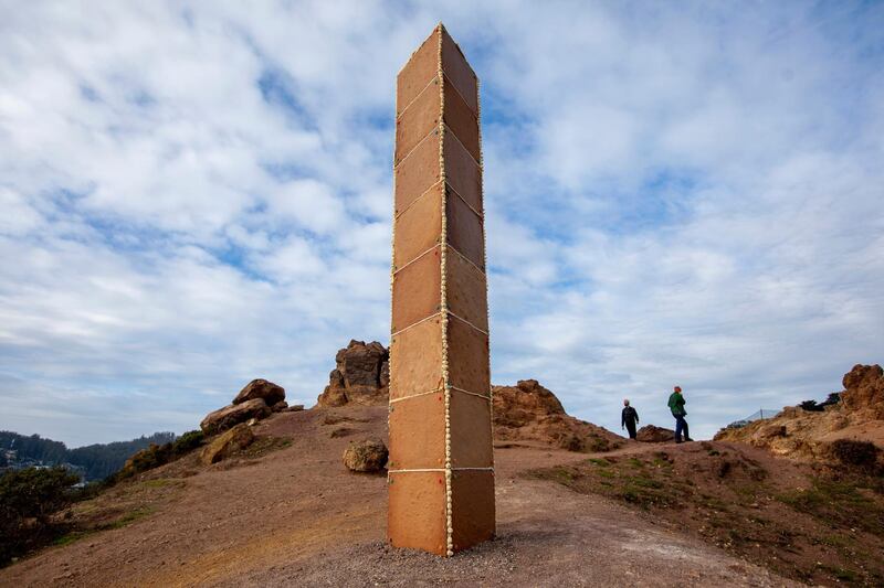 A gingerbread monolith stands on Christmas Day, Dec. 25, 2020, on a bluff in Corona Heights Park overlooking San Francisco. A nearly 7-foot-tall monolith made of gingerbread mysteriously appeared on the San Francisco hilltop on Christmas Day and collapsed the next day. The three-sided tower, held together by icing and decorated with a few gumdrops, delighted the city when word spread about its existence. (Karl Mondon/Bay Area News Group via AP)