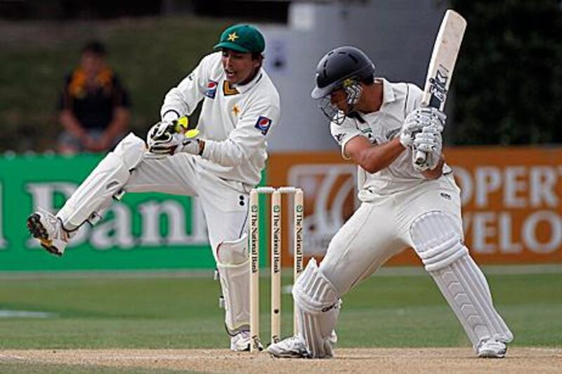 Adnan Akmal, left, fields behind the stumps as New Zealand batsman Ross Taylor looks on.