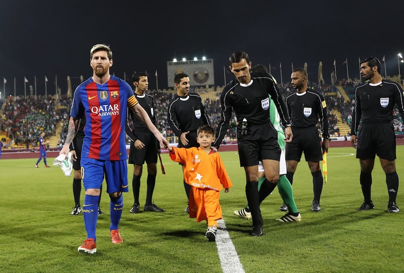 Barcelona’s Lionel Messi holds the hand of Afghan boy Murtaza Ahmadi on the pitch before the start of a friendly football match against Saudi Arabia’s Al Ahli FC in the Qatari capital Doha. Karim Jaafar / AFP