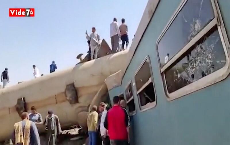 This image provided by Youm7 shows crowds of people gathered around mangled train carriages at the scene of a train accident in southern Egypt. AP Photo