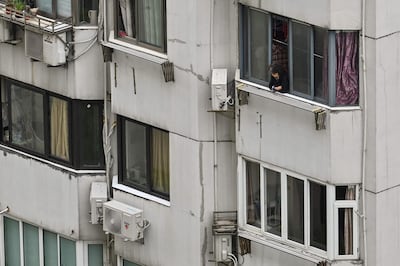 A woman looks out the window of a residential building during a Covid-19 coronavirus lockdown in the Jing'an district in Shanghai on April 23, 2022. The mental health repercussions of the pandemic are still being examined. Hector Retamal  /  AFP