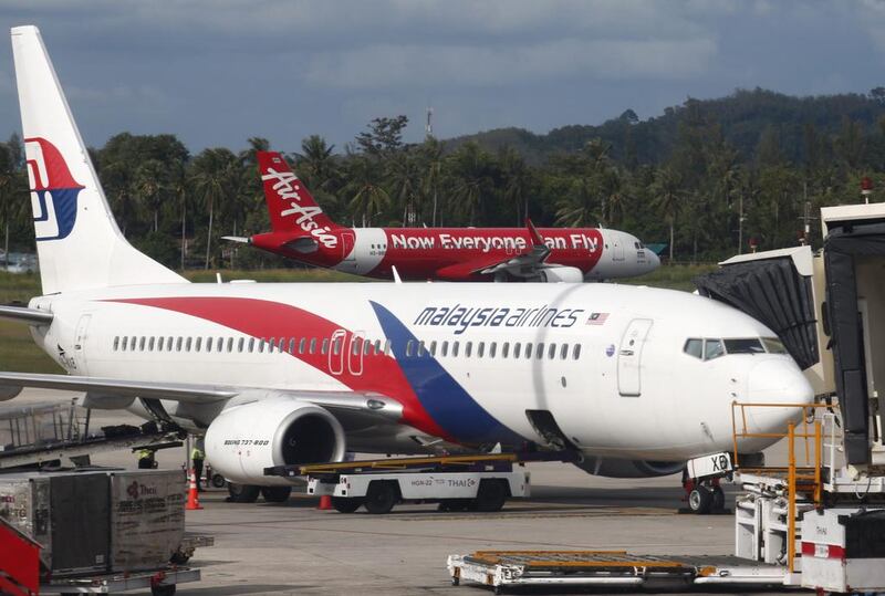 An AirAsia plane is about to take off behind a boarding Malaysia Airlines plane on the resort island of Phuket, southern Thailand. Barbara Walton / EPA