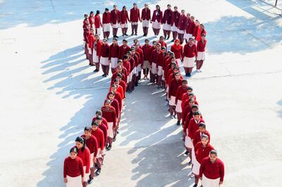 School students pose for a photograph as they stand in the shape of a ribbon as part of an awareness event on the eve of the 'World AIDS Day' in Amritsar on November 30, 2019. / AFP / NARINDER NANU
