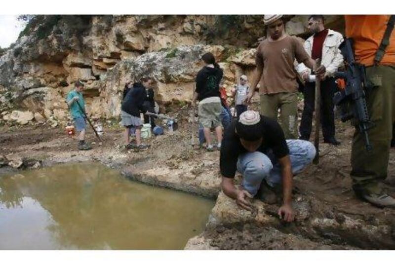 Israeli settlers, protected by armed men, shovel the ground to divert water from a spring in the Palestinian West Bank village of Karawa Bani Hassan, south of Nablus in 2010.