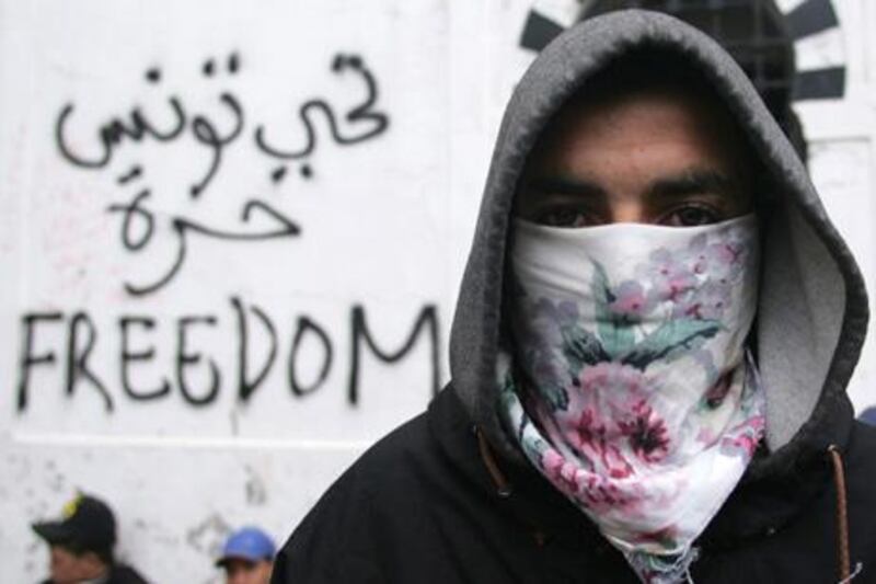A Tunisian protester earlier this month. The words ‘long life to free Tunisia’ have been scrawled in Arabic on the wall behind him.
