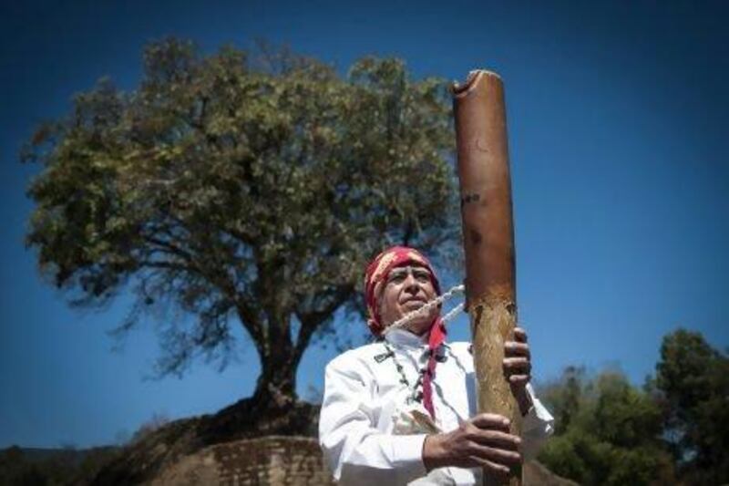 An indigenous man holds a musical instrument during a Maya ceremony in Iximche, Chimaltenango, Guatemala.