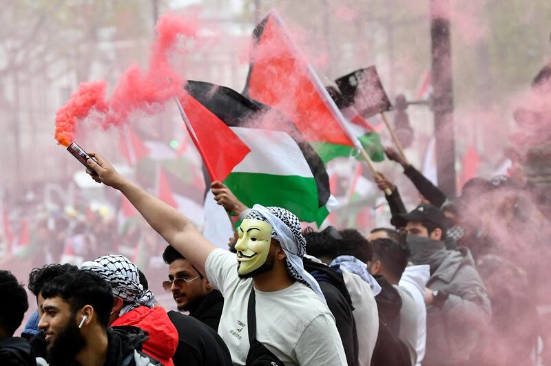 A pro-Palestinian demonstrator wearing a mask holds a flare. Reuters
