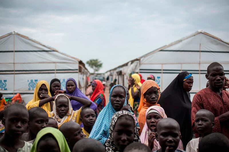 People gather outside a tent in one of the IDP (Internally Displaced People) camps in Pulka on August 1, 2018. - As the presidential race heats up ahead of February polls, the Nigerian government and officials of Borno state, the epicentre of the Boko Haram Islamist insurgency, are encouraging and facilitating the "return" of tens of thousands of people. As he campaigns for a second term in office, the incumbent president is working to show that he has delivered on his pledge to defeat the Islamists. But the reality is that people are being sent back to camps across Borno state while Boko Haram is still launching devastating attacks against military and civilian targets. Pulka is a garrison town built on a model becoming increasingly common across Nigeria's remote northeast region: a devastated town turned into a military base so soldiers can protect satellite camps and humanitarian agencies can distribute aid. (Photo by Stefan HEUNIS / AFP)