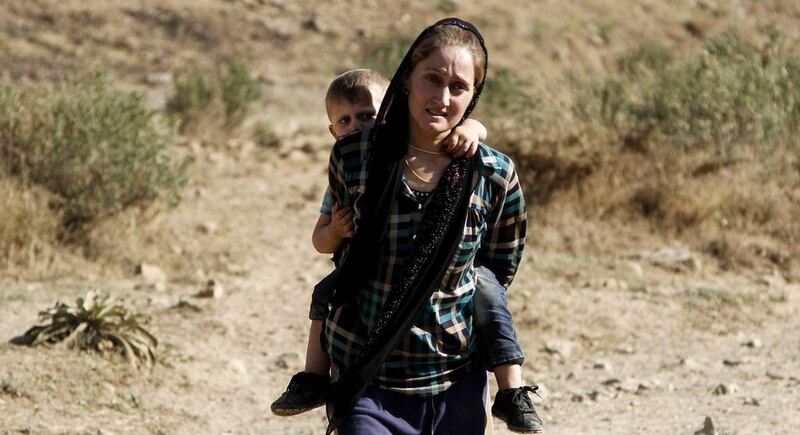A Yazidi refugee fleeing Iraq woman carries her son on her back at the Turkish-Iraqi border on August 17, 2014. Ulas Yunus Tosun/EPA