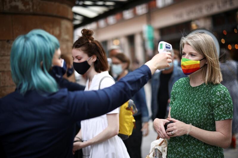 People have their temperature checked while queuing for the West End show 'The Show Must Go On' at the Palace Theatre, in London. Reuters