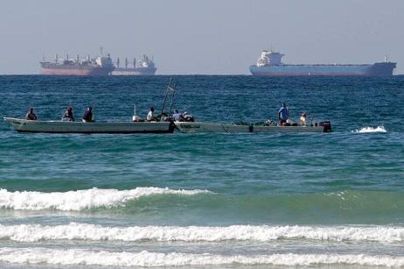 In this Jan. 19, 2012 photo, fishing boats are seen in front of oil tankers on the Persian Gulf waters, south of the Strait of Hormuz, offshore the town of Ras Al Khaimah in United Arab Emirates. Even as sanctions squeeze Iran ever tighter, there's one clandestine route that remains open for business: A short sea corridor connecting a rocky nub of Oman with the Iranian coast about 35 miles (60 kilometers) across the Gulf. (AP Photo/Kamran Jebreili) *** Local Caption ***  Mideast Hormuz Strait Smugglers.JPEG-003ee.jpg