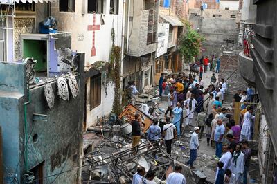 Police officials and residents stand amid debris beside the torched Saint John Church in Jaranwala on Thursday. AFP