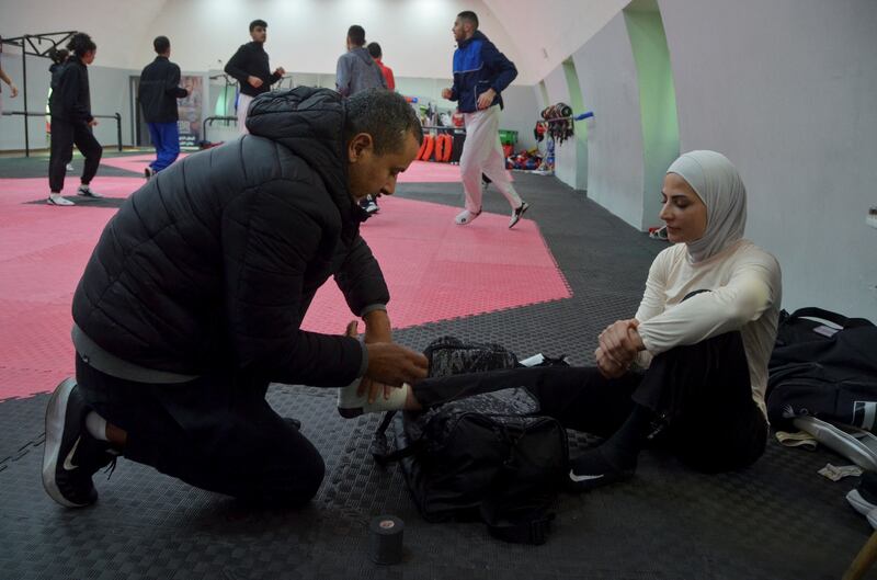 A physical therapist assists Alsadeq during a training session