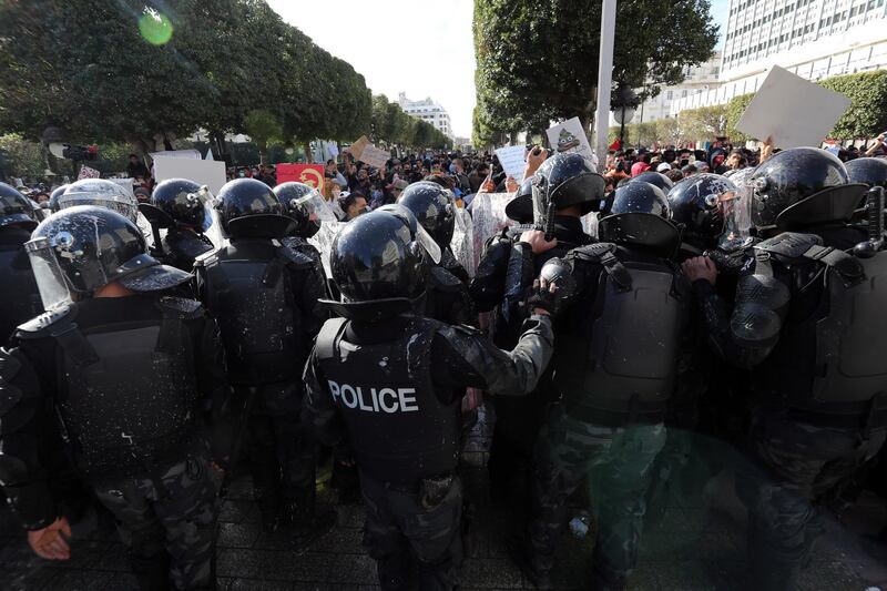 Tunisian anti-riot policemen block the way in front of protesters during a demonstration in Tunis. EPA