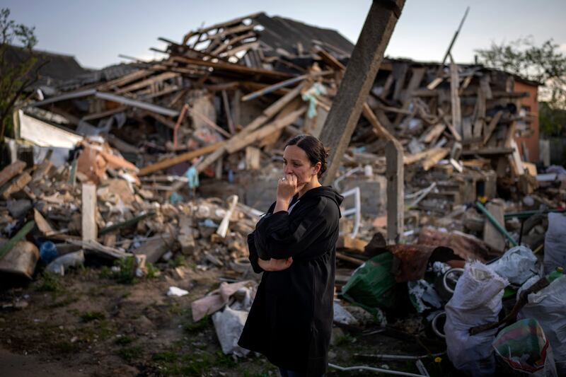 A woman stands next to her home in Irpin, near Kyiv, after it was nearly completely destroyed by Russian bombing. AP