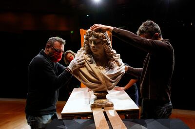 Workers handle a bust of Charles Le Brun by French sculptor Antoine Coysevox, in the Louvre museum, in Paris, Wednesday, Feb. 17, 2021. It's uncertain when the Louvre will reopen, after being closed on Oct. 30 in line with the French government's virus containment measures. But those lucky enough to get in benefit from a rarified private look of collections covering 9,000 years of human history -- with plenty of space to breathe. (AP Photo/Thibault Camus)
